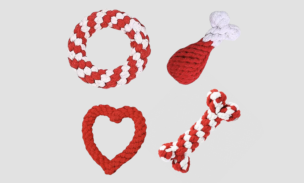 Four braided dog toys in red and white: a round ring, a bone shape, a heart shape, and a rope bone, all designed for playful dogs. Visit dogtags.co.uk for personalised dog tags.